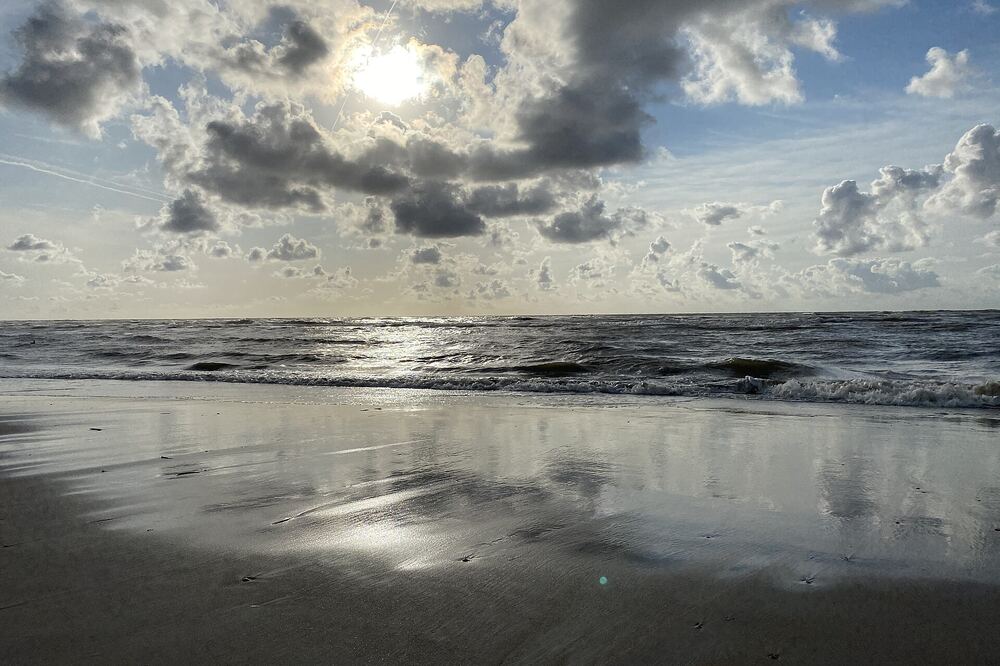 Het natte strand van Zandvoort waarin de laagstaande zon weerspiegelt