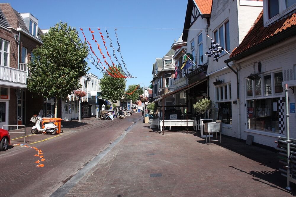 Een Zandvoortse winkelstraat met vlaggetjes boven de straat onder een blauwe lucht